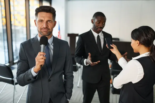 A journalist interviews a businessman in a conference room, capturing a professional and political setting. Brand reputation management: a practical guide for 2027
