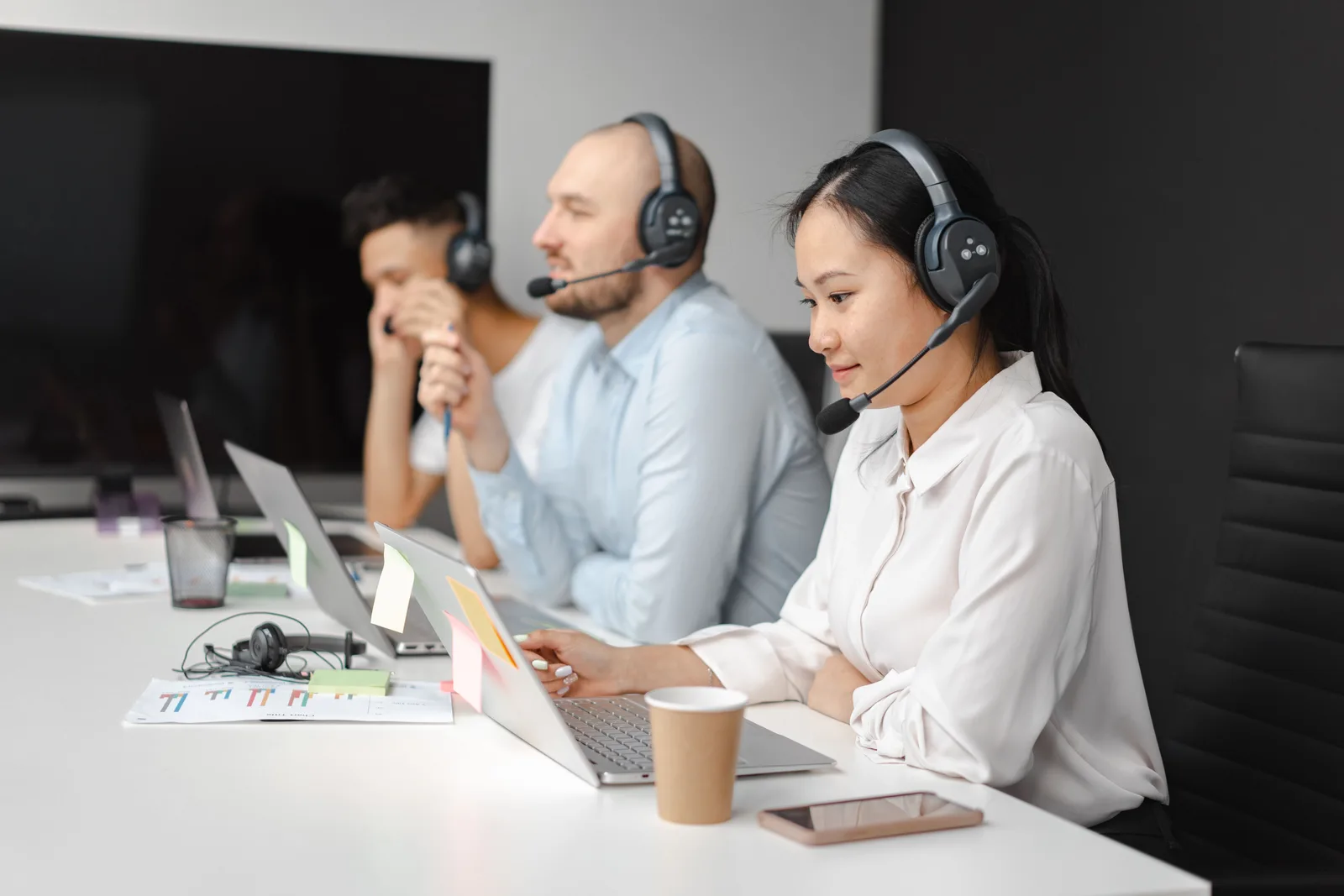 Call center agents wearing headsets working on laptops at a customer support team meeting. Brand reputation management benchmarks: the numbers and what sits behind them