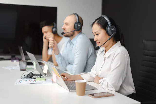 Call center agents wearing headsets working on laptops at a customer support team meeting. Brand reputation management benchmarks: the numbers and what sits behind them
