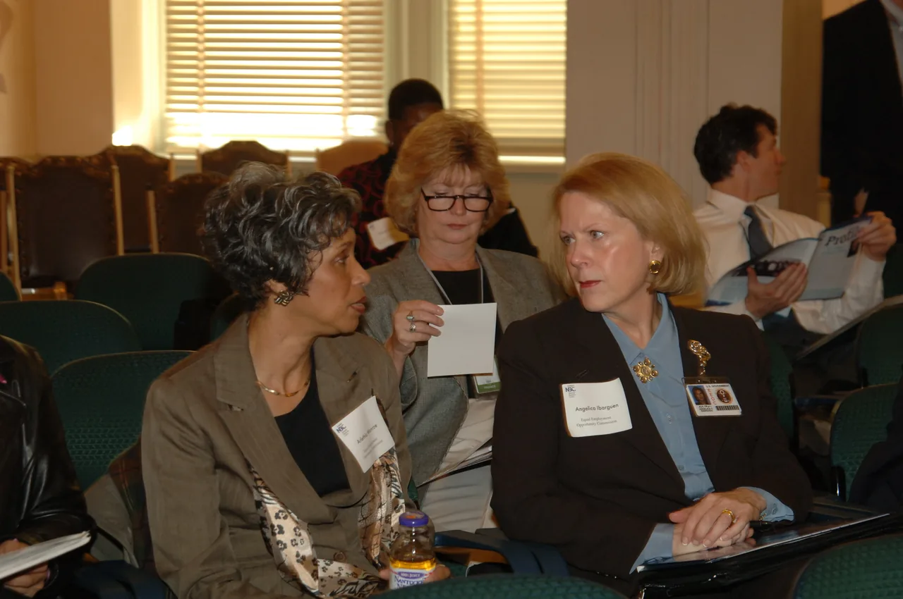Colleagues speak in audience seating during a customer service meeting.